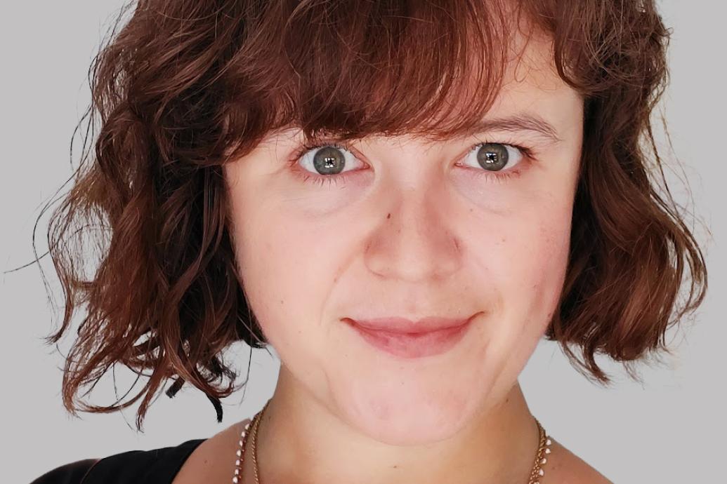 A headshot of a person against a gray background