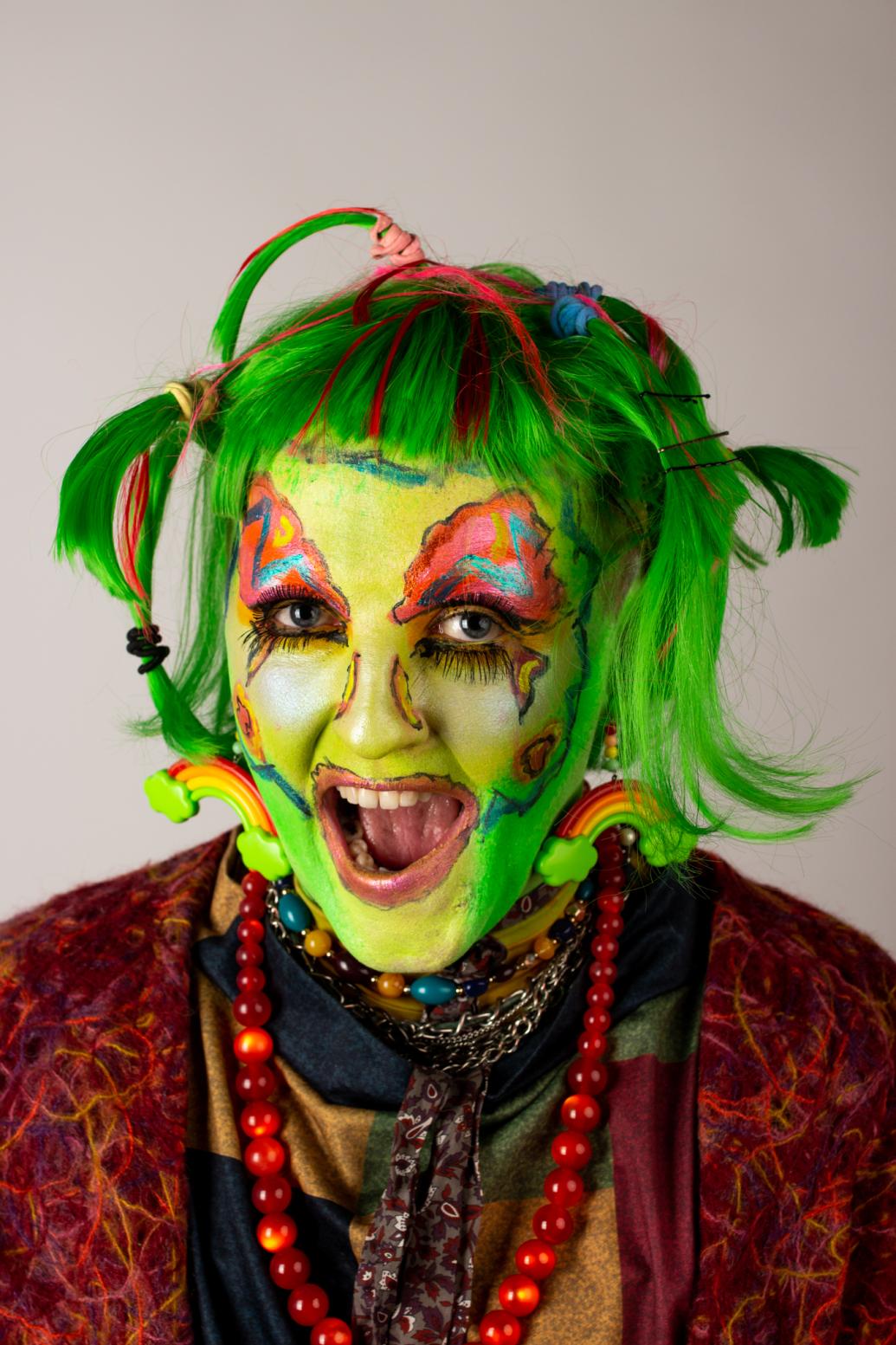 A person dressed as a goblin with green hair and make up 