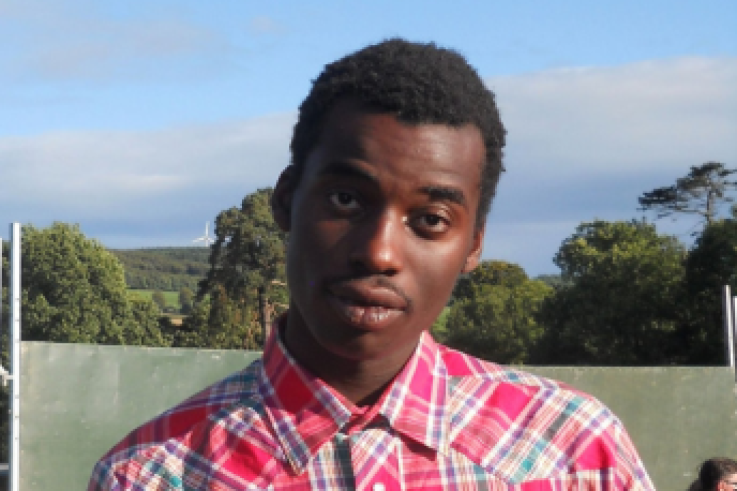 A man in a plaid shirt stands in a vibrant field, enjoying the serene landscape and the fresh air around him.